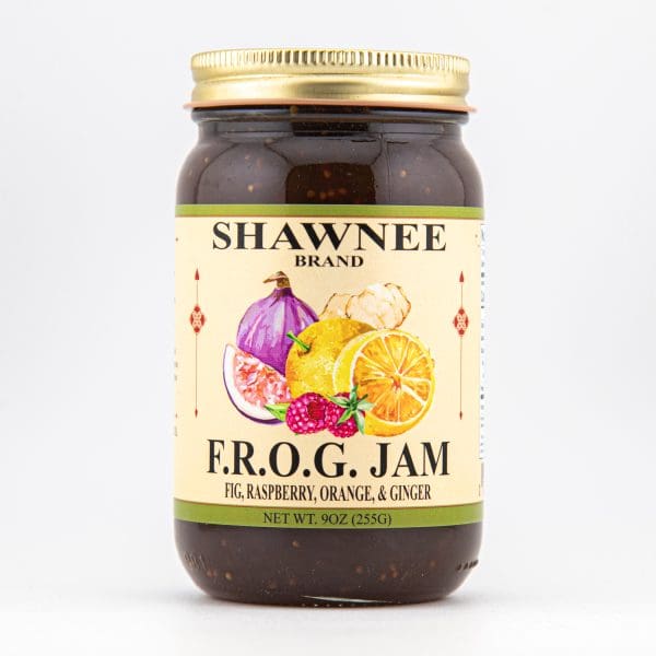 A jar of Shawnee Brand F.R.O.G. Jam, featuring fig, raspberry, orange, and ginger, with colorful fruit illustrations on the label.